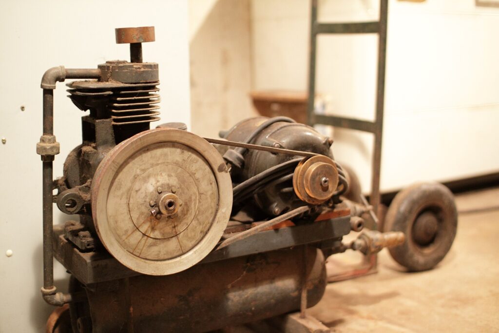 Old belt-driven piston air compressor on its receiver tank