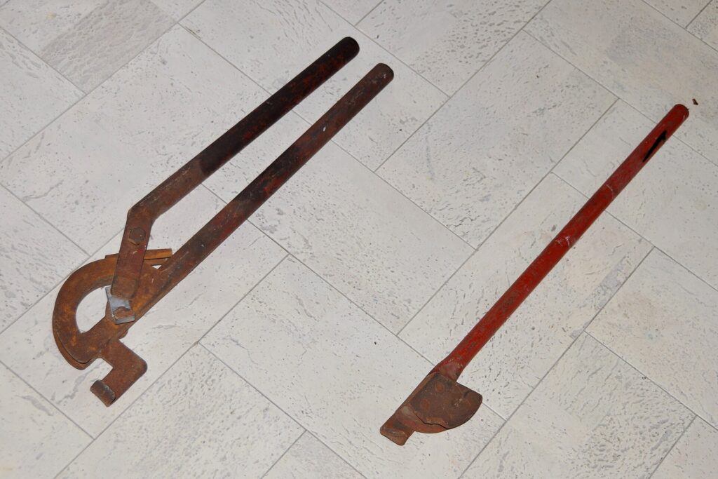 Hand pipe-bending machine and its grooved bending block on a tiled floor