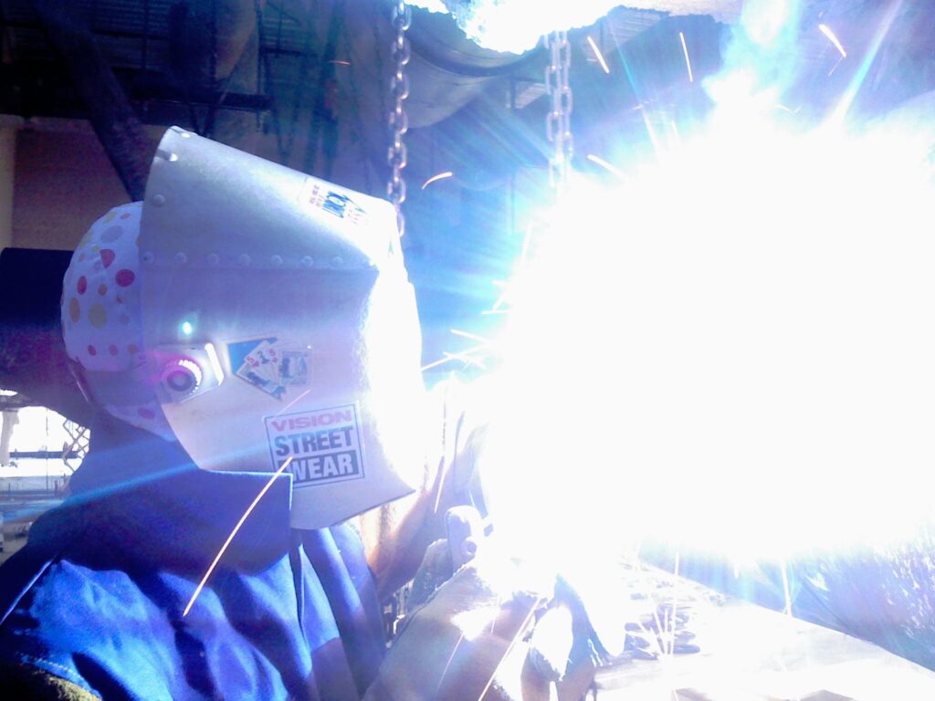 Pipefitter welding steel HVAC pipe on a construction site
