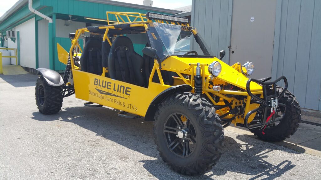 Yellow tube-frame sand rail buggy parked outside a workshop