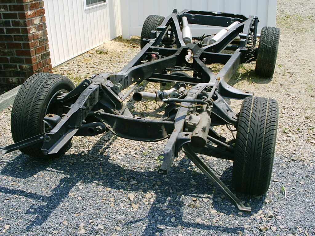 Bare vehicle ladder chassis with suspension, wheels and part of a bent-pipe exhaust