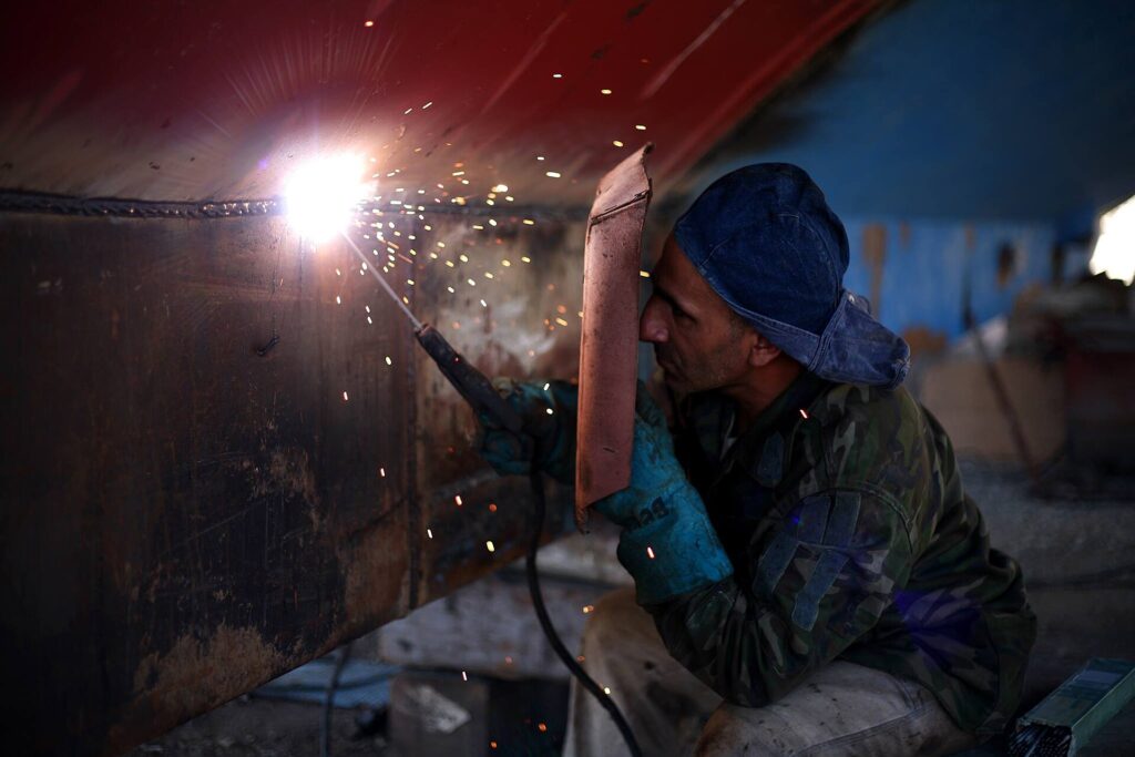 Welder working on a steel sheet in a workshop