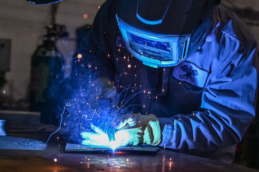 Welder wearing a welding helmet while welding metal
